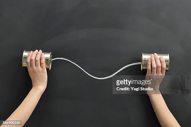 hands holding the cans on a blackboard - tin can phone stock pictures, royalty-free photos & images
