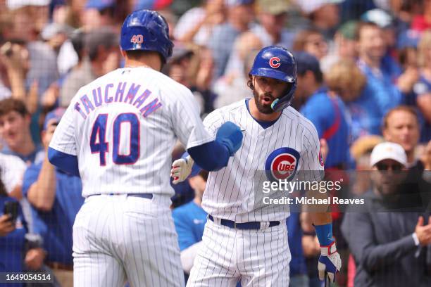 Mike Tauchman of the Chicago Cubs high fives Dansby Swanson after scoring a run on a RBI double by Ian Happ during the first inning against the...