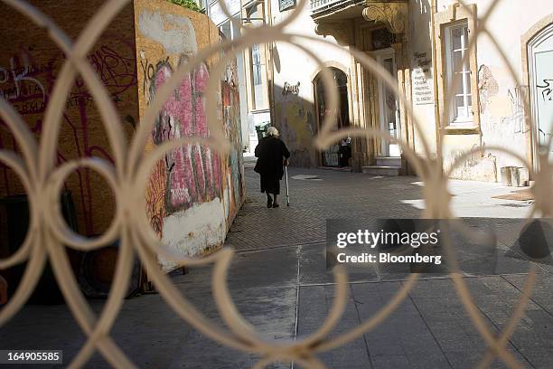 An elderly lady passes a graffiti covered wall as she walks down a side street in Nicosia, Cyprus, on Friday, March 29, 2013. Cypriots face a second...