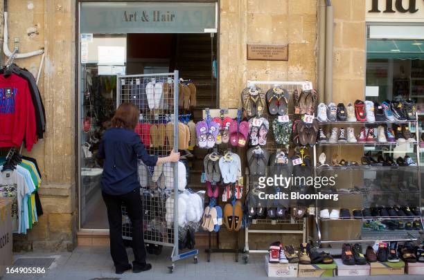 An employee sets up an outdoor display of shoes ahead of opening at a store on Ledra Street in Nicosia, Cyprus, on Friday, March 29, 2013. Cypriots...