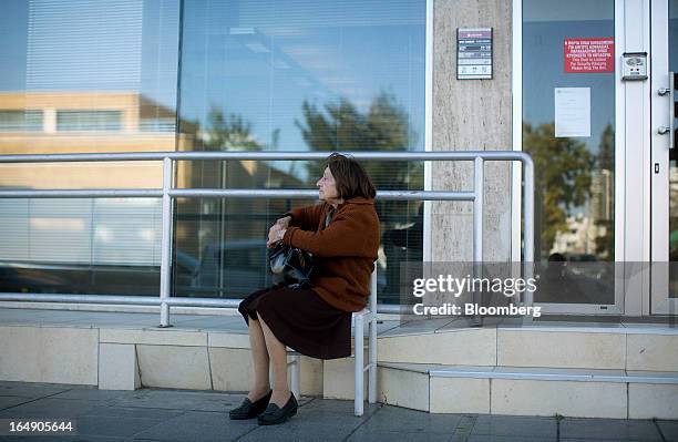 An elderly customer sits and waits for a branch of a Cyprus Popular Bank Pcl, also known as Laiki Bank, to open in Nicosia, Cyprus, on Friday, March...