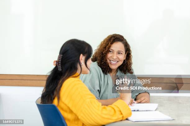 female professor listens to student during tutoring session - school counselor stock pictures, royalty-free photos & images