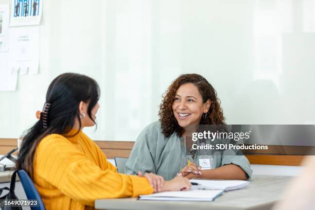 college professor tutors student after class - schoolbegeleider stockfoto's en -beelden
