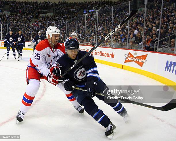 Derek Meech of the Winnipeg Jets drives past Jason Chimera of the Washington Capitals as the puck slides around the boards during second period...