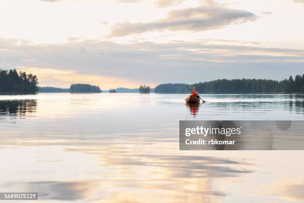 travel on the lake - tourist rowing a canoe at sunset - finland landscape stock pictures, royalty-free photos & images