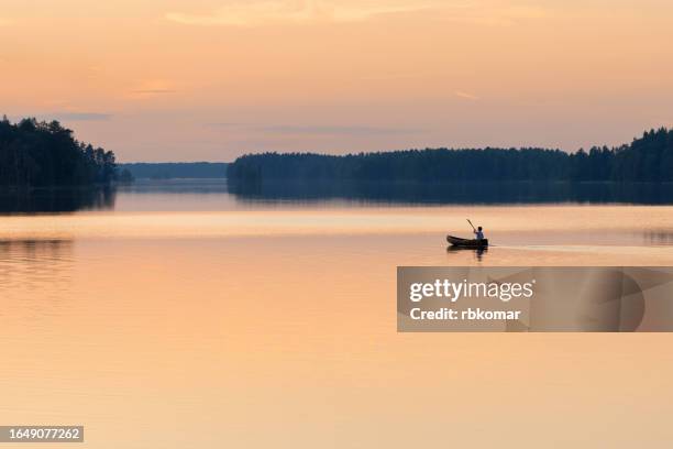 canoeing on a serene lake during a majestic sunset - girl rowing boat photos et images de collection