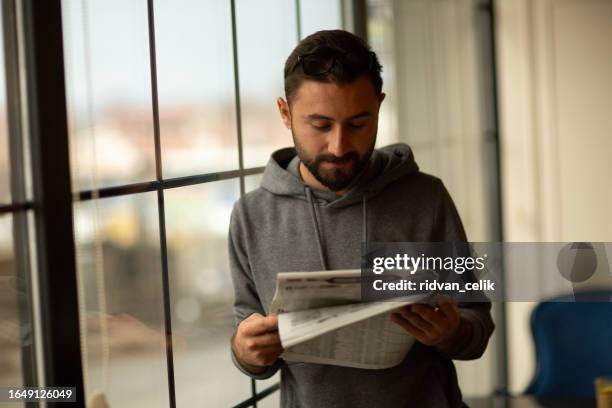 frühstück im café - junger mann liest zeitung stock-fotos und bilder