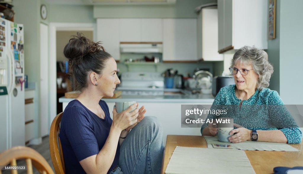 Young woman chatting with her mom over tea during a visit