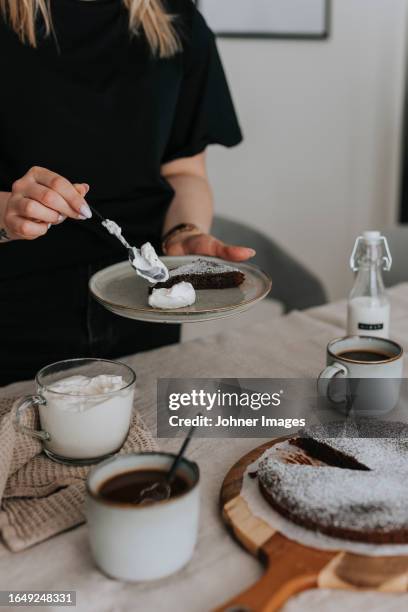 woman adding whipped cream to chocolate cake - whip cream cake - fotografias e filmes do acervo