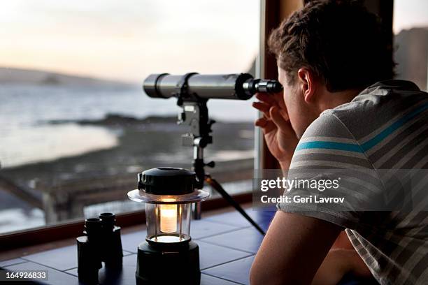 man looking through a telescope - lantern water stock-fotos und bilder