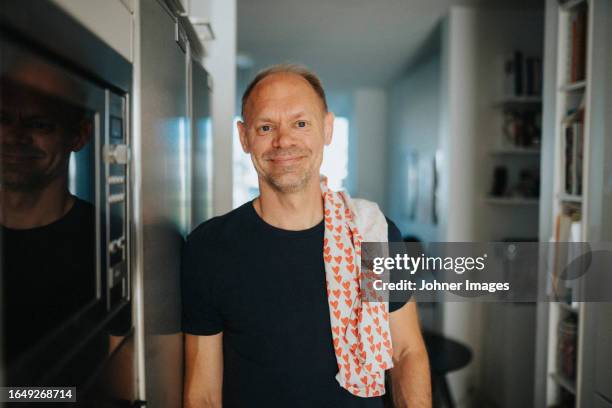 portrait of smiling mature man doing housework in kitchen - dish towel bildbanksfoton och bilder