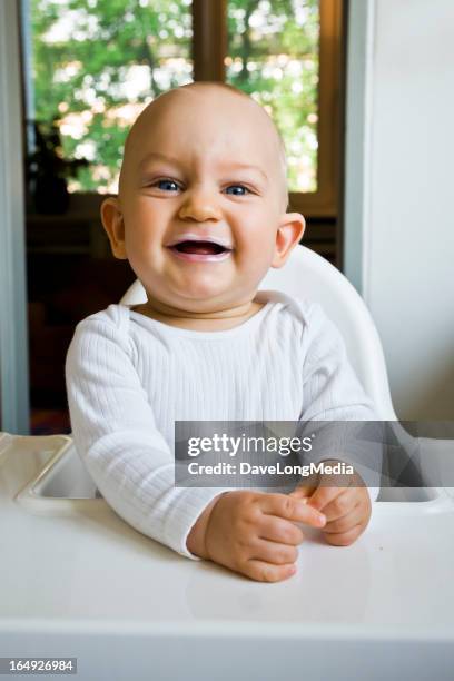 baby smiling in high chair - baby eating yogurt stockfoto's en -beelden