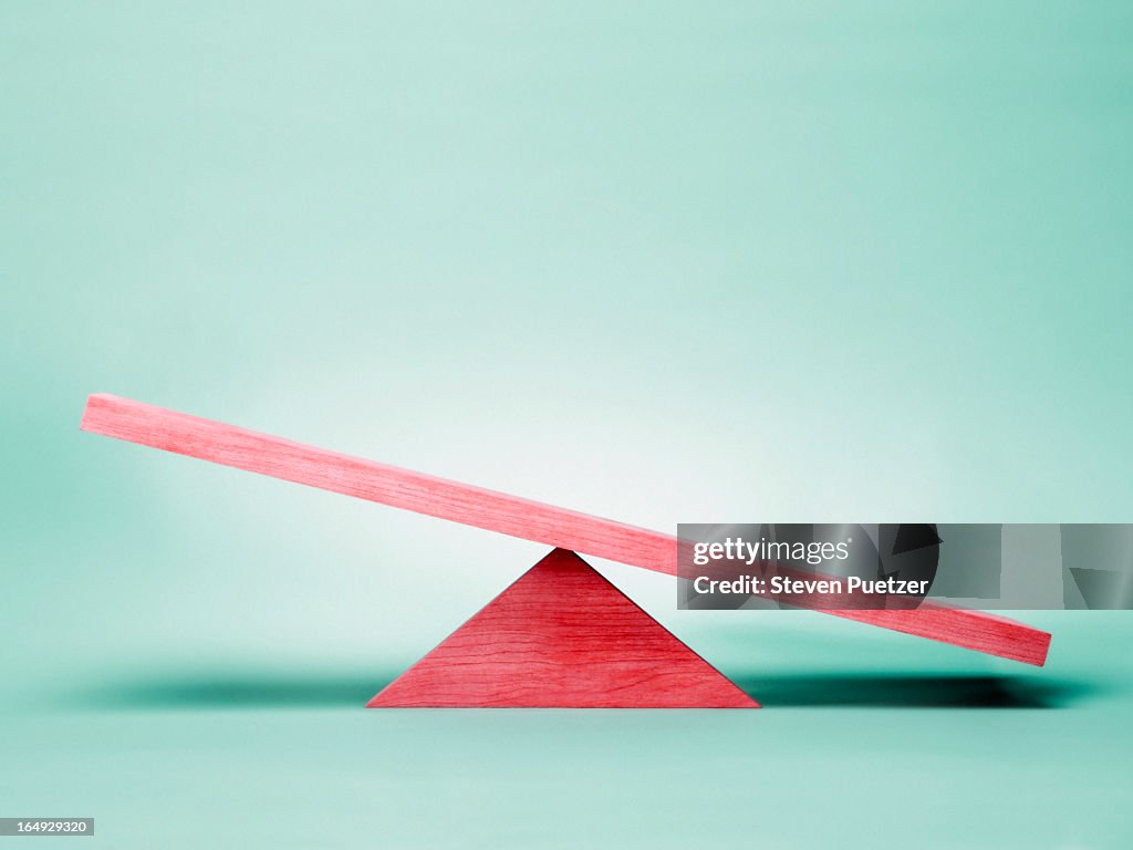 Empty red seesaw on green background
