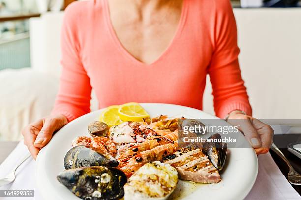 woman eating grilled seafood in a restaurant - clam seafood stock pictures, royalty-free photos & images
