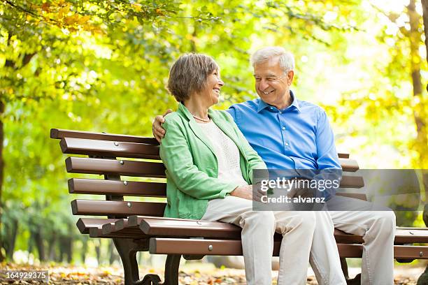 senior couple enjoying time together at the park - park bench stock pictures, royalty-free photos & images