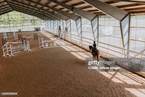 view of horse rider using indoor riding paddock - paddock stock pictures, royalty-free photos & images