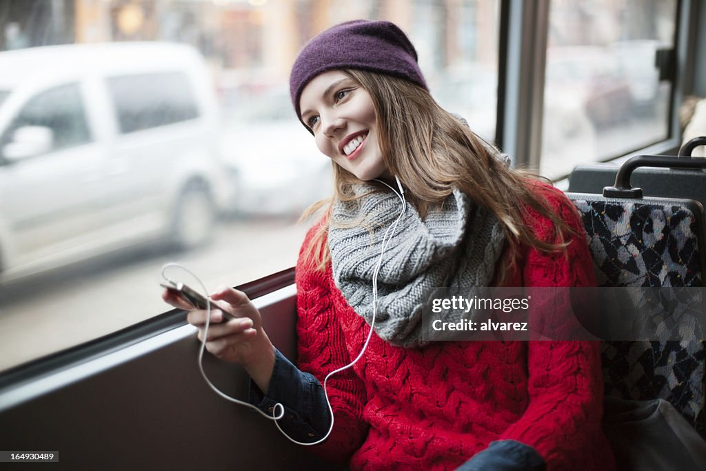 若い女の子の彼女のリラクゼーションに電話での公共交通機関