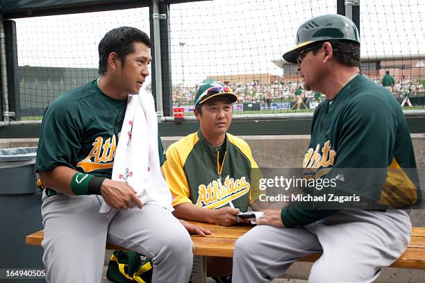 Third Base Coach Mike Gallego of the Oakland Athletics talks with Hiroyuki Nakajima and interpreter Hiroo Nishi during a spring training game against...