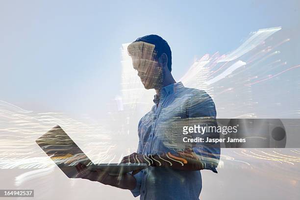 double exposure of man using laptop and cityscape - mehrfachbelichtung bewegung stock-fotos und bilder