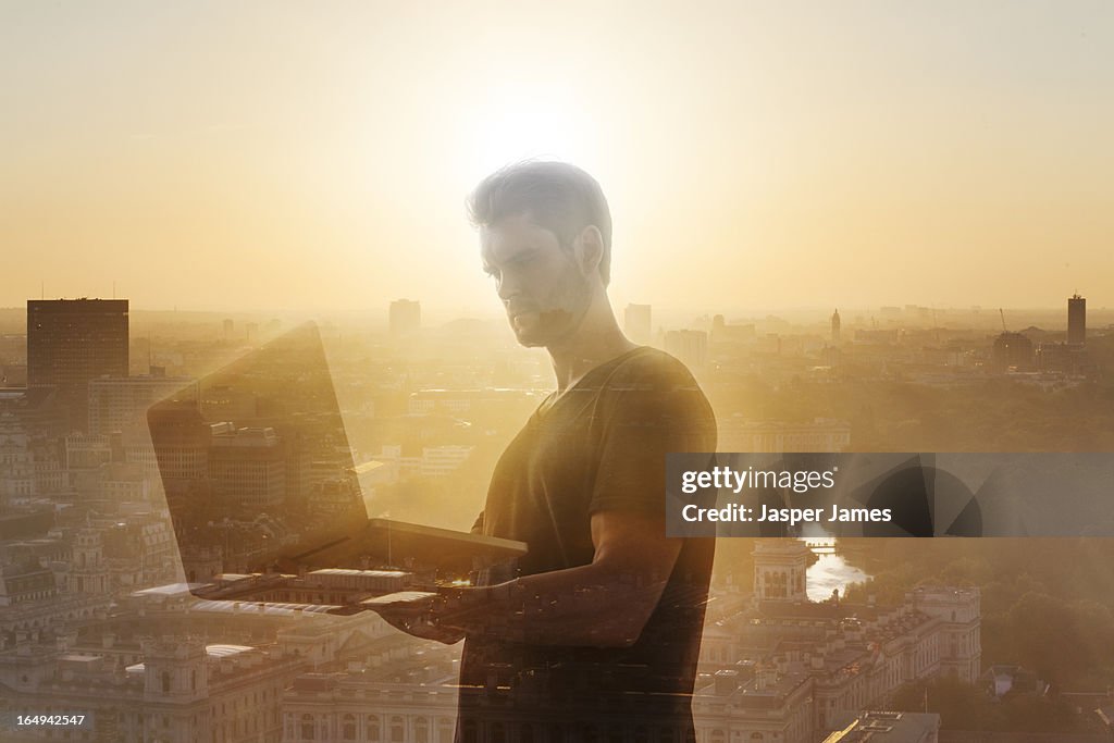 Composite of man using laptop and cityscape