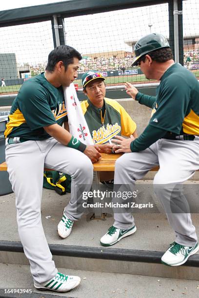 Third Base Coach Mike Gallego of the Oakland Athletics talks with Hiroyuki Nakajima and interpreter Hiroo Nishi during a spring training game against...