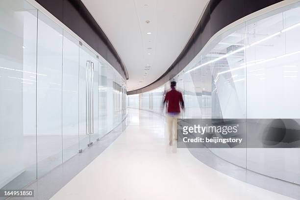 out of focus man walking down modern corridor - floor walk business stock pictures, royalty-free photos & images