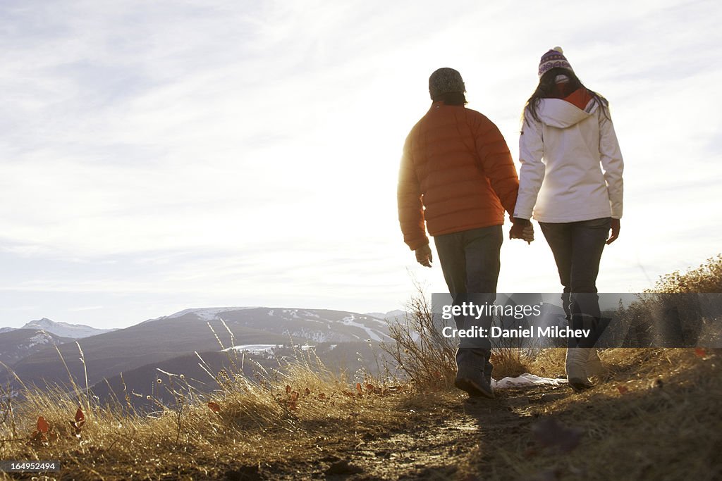 Couples holding hands, while waling on a trail.