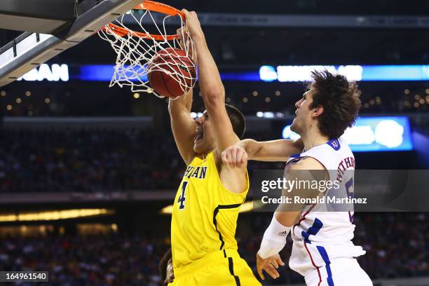 Mitch McGary of the Michigan Wolverines dunks past Jeff Withey of the Kansas Jayhawks in the first half during the South Regional Semifinal round of...