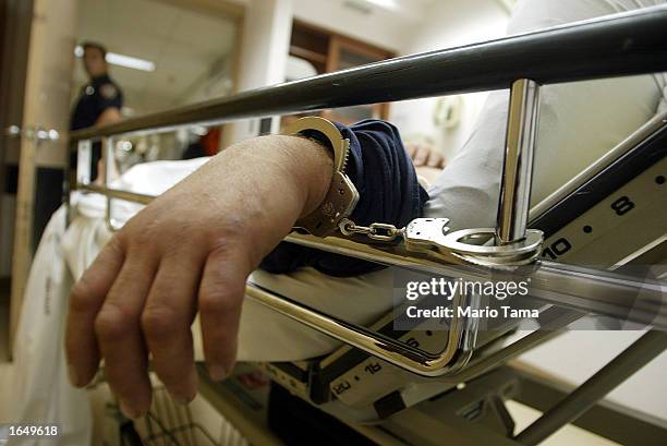 Handcuffed suspect is watched over by a police officer in the emergency room at Coney Island Hospital September 5, 2002 in the Brooklyn borough of...