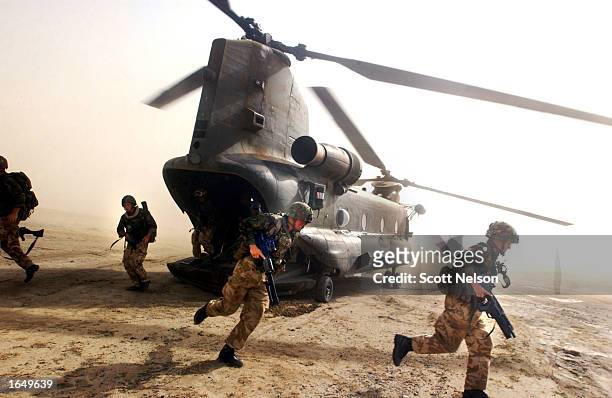 British Royal Marines of 45 Commando scramble out the back of a Chinook helicopter during an eagle vehicle check point operation as part of the...