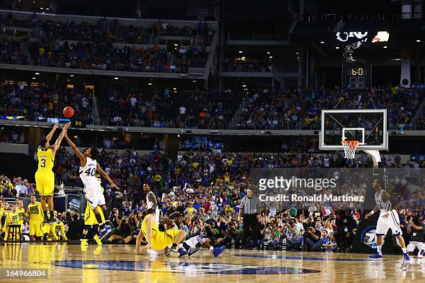 Trey Burke of the Michigan Wolverines shoots a game tying three pointer in the final seconds of the second half over Kevin Young of the Kansas...