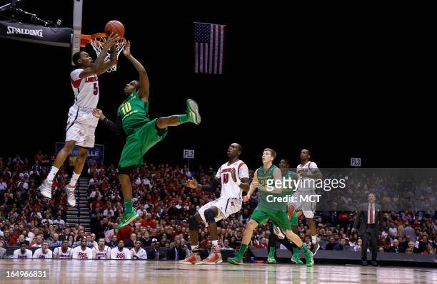 Louisville guard Kevin Ware looks to kick the ball out against pressure from Oregon guard Johnathan Loyd in second half action in their NCAA fourth...