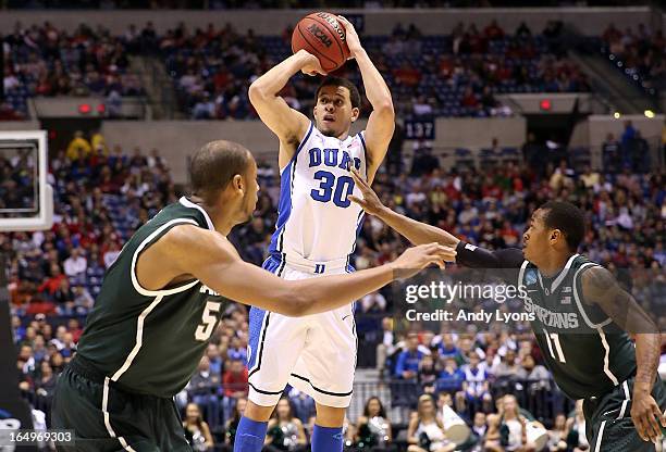 Seth Curry of the Duke Blue Devils attempts a shot over Adreian Payne and Keith Appling of the Michigan State Spartans during the Midwest Region...