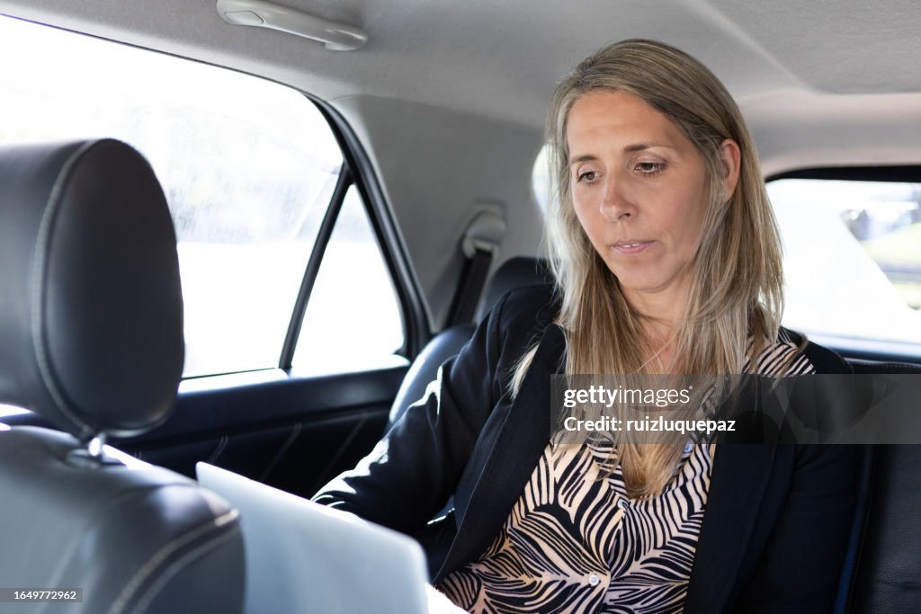 Businesswoman using laptop in a car