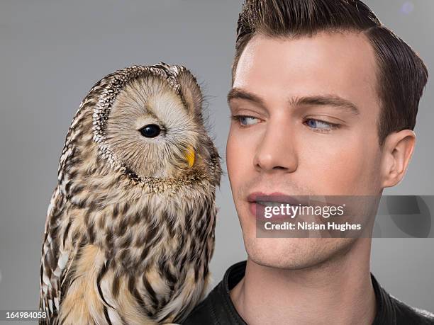 portrait of man with owl perched on shoulder - looking over shoulder stockfoto's en -beelden