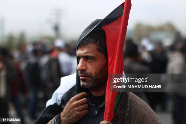 Palestinian man holds his national flag over his head as he takes part in a rally marking Land Day in Beit Hanun in the northern Gaza Strip on March...