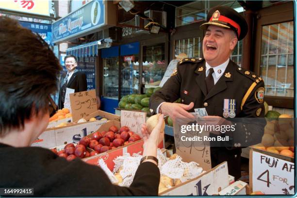 Fantino tours China town . Trying his hand as a fruit vendor he offers Mabel Sin of the Chinese consultative committee , touring the street with...