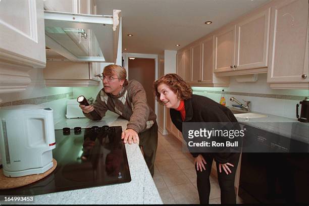 Jeff Clarke uses a combustable gas detector to check possible gas fireplace gas leaks . Condo owner Helen Fain watches ,, in the kitchen venting over...
