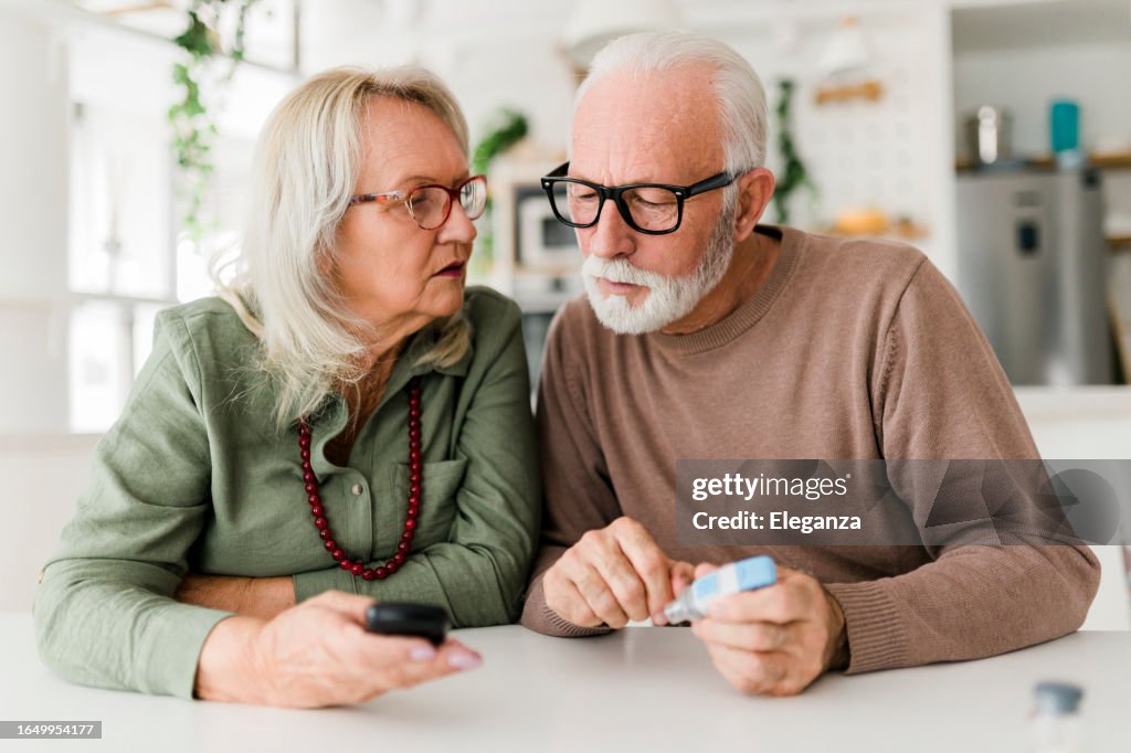 Senior couple using lancet on finger for checking blood sugar level by Glucose meter, Healthcare and Medical, diabetes, glycemia concept