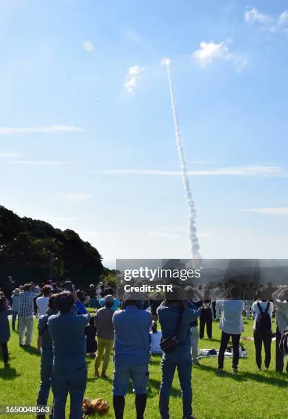 People watch the launch of a H-IIA rocket carrying a small lunar surface probe and other objects, near the Tanegashima Space Centre on Tanegashima...
