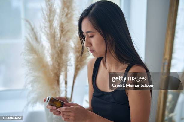 sad depressed young asian woman holding bottle with pills, suffering from depression, taking antidepressants. mental health medications - prozac stock pictures, royalty-free photos & images