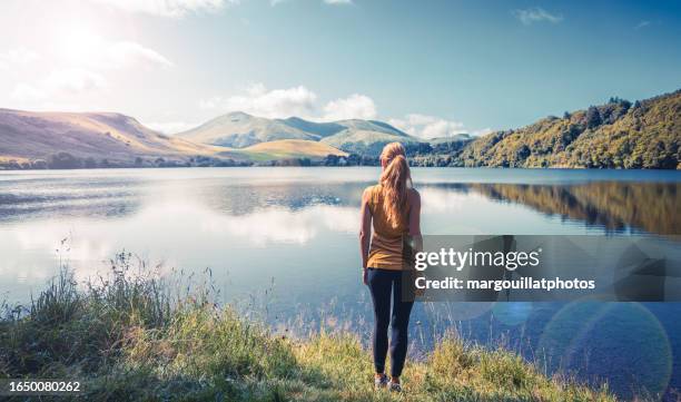 Woman standing enjoying view of lake- Auvergne in France ( Guery lake)- travel, relaxing, calm landscape concept