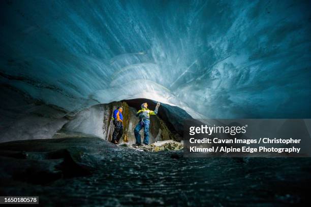 two men marvel at frozen river of ice below a melting glacier - geologist ストックフォトと画像