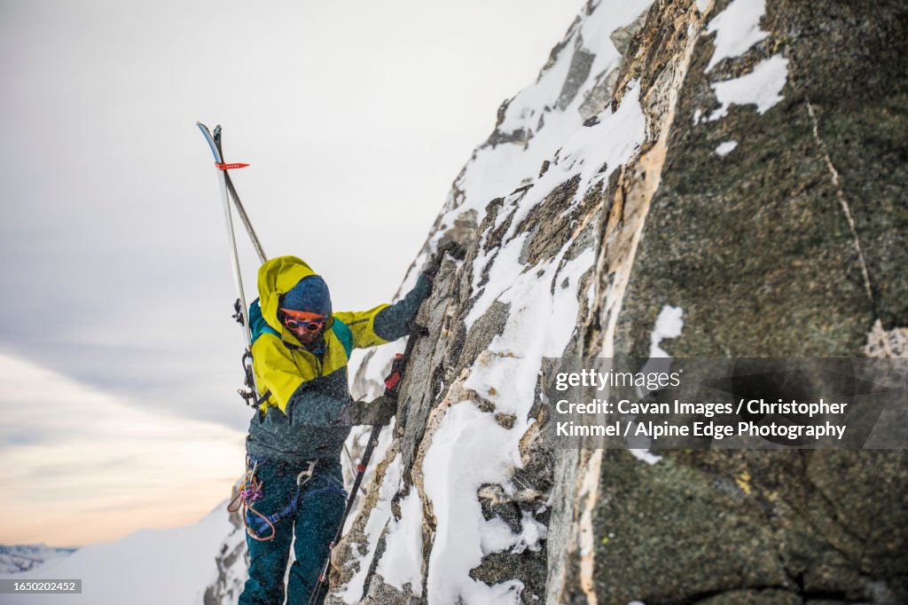 Skier carefully navigates a cliff face on approach to the summit