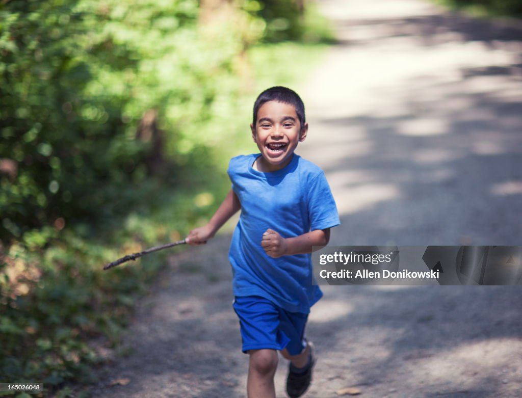 Happy boy running and laughing in forest trail