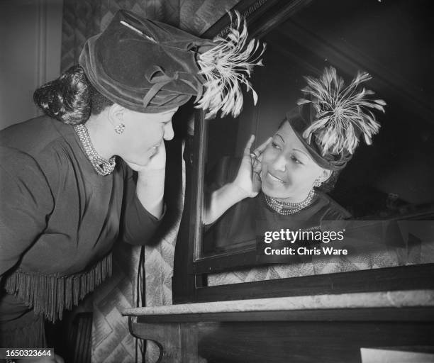 American R&B singer and pianist Nellie Lutcher tilting her head and looking in a mirror, London, November 1950. Lutcher is in the United Kingdom for...