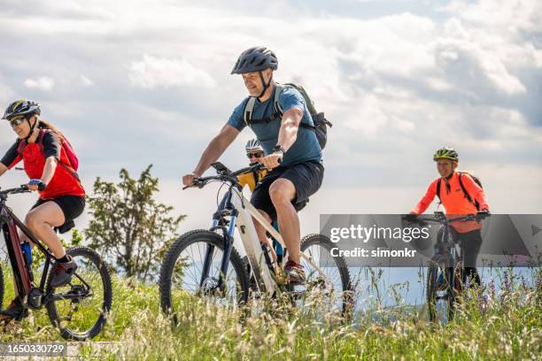 smiling couples riding electric bikes - vitaliteit fiets stockfoto's en -beelden