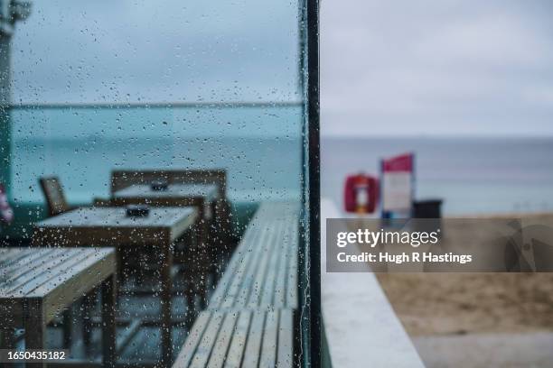 Rain-spattered windows and empty tables at the cafe on Gyllyngvase Beach on August 31, 2023 in Falmouth, England. New figures suggest that visitor...