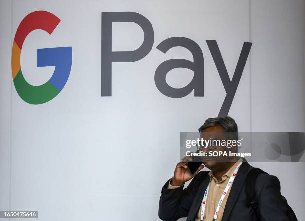 Man talking on his phone walks below the logo of 'G pay' at Global Fintech Fest in Mumbai. Global Fintech Fest is a worldwide platform where...