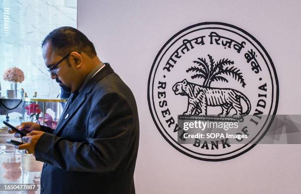 Man checks his mobile phone near 'Reserve Bank of India' logo at Global Fintech Fest in Mumbai. Global Fintech Fest is a worldwide platform where...